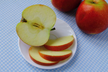 Some pieces of an apple on the plate with additional apples