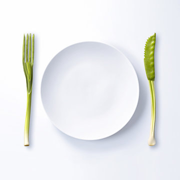 Couverts form&eacute;s de l&eacute;gumes verts et assiette blanche