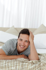 Portrait of a cheerful man lying on his bed