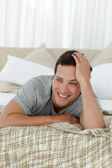 Happy man smiling lying on his bed