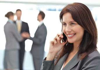 Happy businesswoman on the phone while her team is working