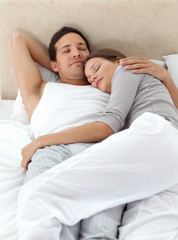 Obraz na płótnie Canvas Cute couple sleeping in each other's arms on their bed