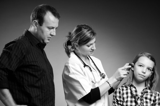 Doctor Examining Girl Ear And Father Looking