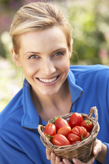 Young woman posing with tomatoes in garden