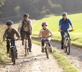 Fototapeta premium Young parents with children ride bikes in park