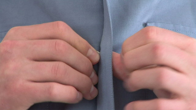 Close up of male buttoning his shirt