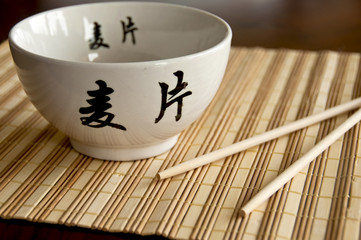 Chinese white bowl and sticks on bamboo mat