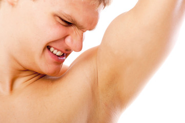 closeup of young man sniffing his armpit isolated on white - obrazy, fototapety, plakaty
