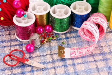 Fototapeta na wymiar Coloured bobbins of threads, woolen balls and cushion for pins i