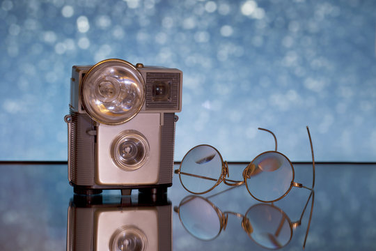Old camera with flash bulb and antique glasses