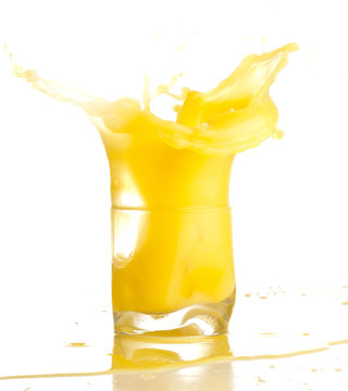 orange juice splashing on a glass on white background