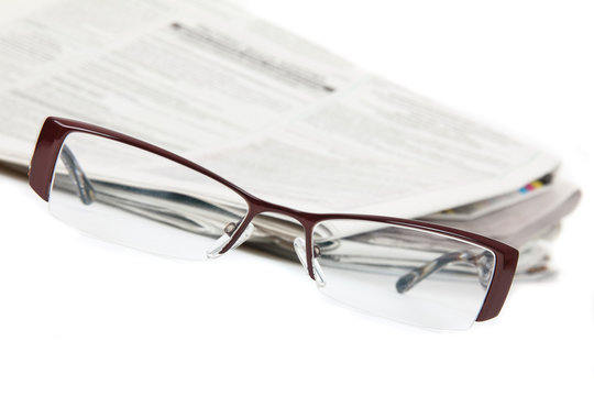Modern eyeglasses and newspaper isolated on white