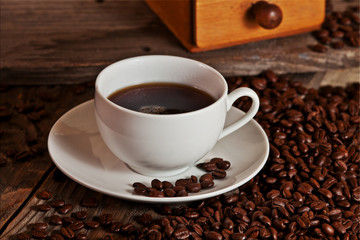 Cup of rich coffee sits on a mound of beans.