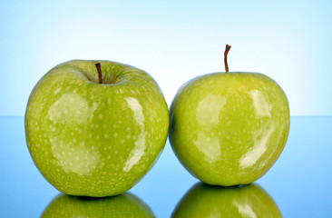 Two green apples on blue background