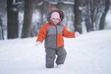 Fototapeta na wymiar cute baby walk through fresh deep snow in park