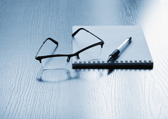 Eyeglasses with notepad and pen on the table