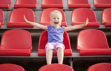 Young pretty girl cries and sitting on the audience bleachers