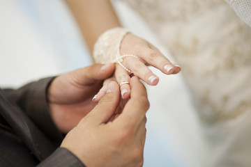 The groom wears a wedding ring bride