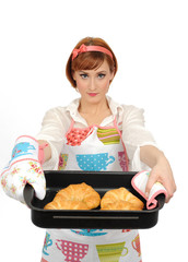 Beautiful cooking woman in apron eating fresh made croissant bre