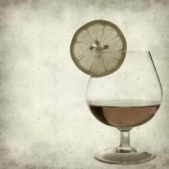 textured old paper background with cognac in a snifter glass