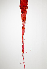 Red liquid pouring out of a glass bottle