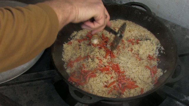 Stirring pilaf with spoon, removing garlic from Cauldron