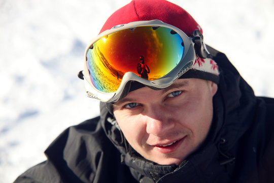 Close-up portrait of snowboarder sitting on snow