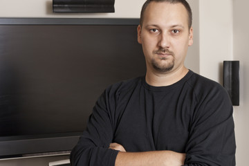 man with mustache and beard standing in front of  television