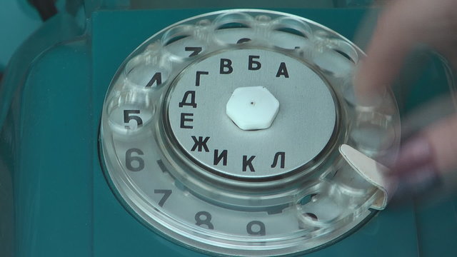 Ladies hand dials the number on the old phone.