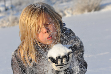 Kind beim Schnee pusten