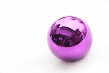 Eine lila Weihnachtskugel im Schnee