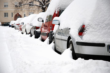 Snow covered cars parked on a street in a town