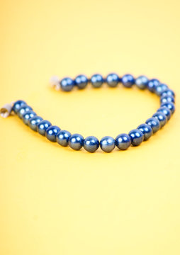 String of beads of blue in yelloy background