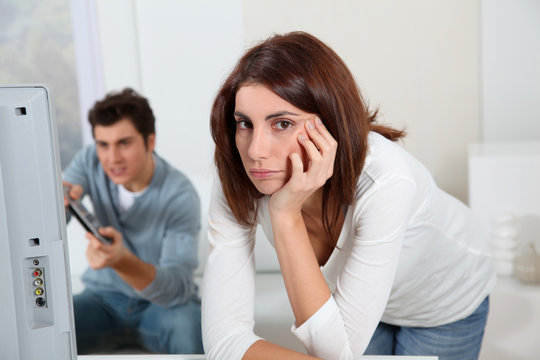 Young woman fed up with boyfriend playing video game