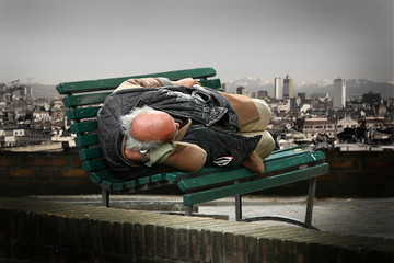 clochard che dorme sopra una panchina