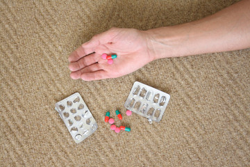 Pills and a hand on a carpet.