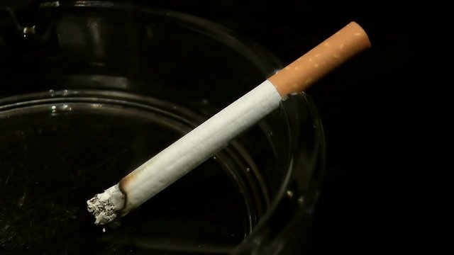 Zigarette im Aschenbecher brennt im Zeitraffer ab - Schwarz