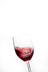 Red wine swirling in glass on white background