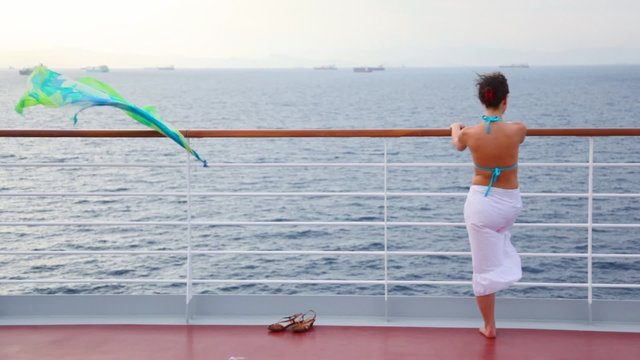 woman stands on deck of cruise liner