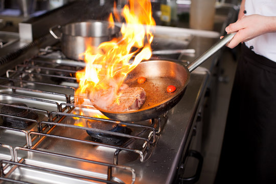 koch flambiert fleisch in der pfanne
