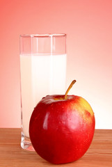 Fresh red apple and milk on a wooden stand with red background