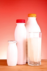 some white bottles with milk products and a glass of milk on a w