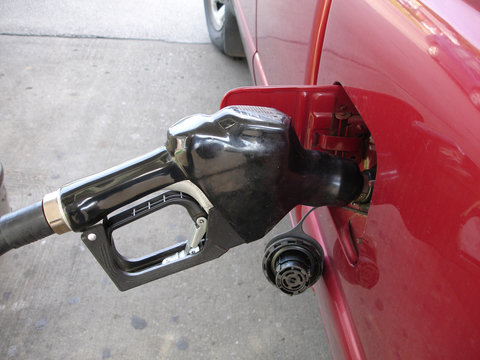 Gas pump nozzle filling up vehicle with gas.