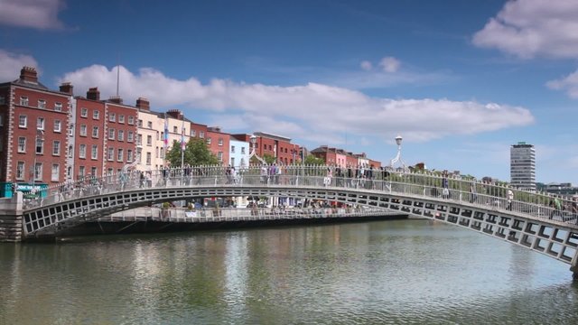 people walking on Ha'penny Bridge across River Liffey in Dublin