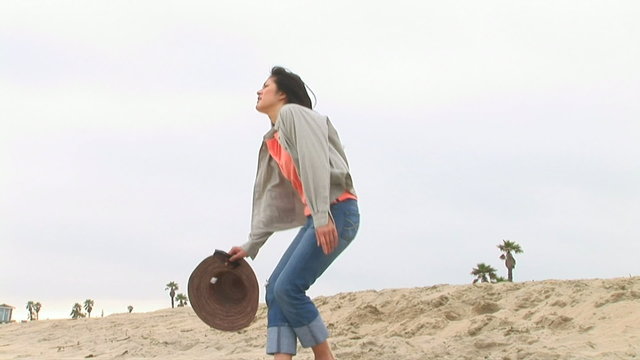 Young woman sitting on sand dunes at beach in cool weather