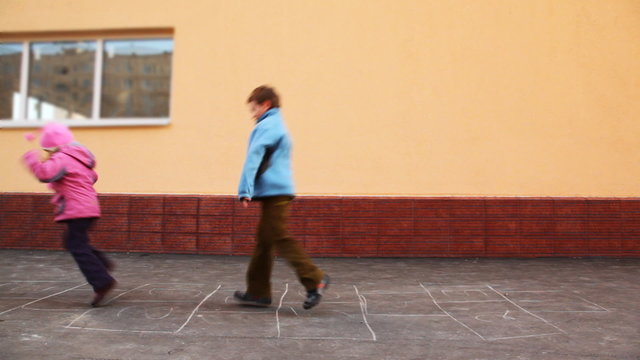 Boy And Girl Playing Hopscotch Jumping