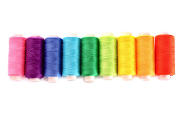 Pile of coloured bobbins of lurex thread isolated on white