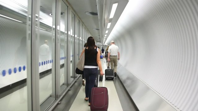 Back view of walking people with bags on escalator