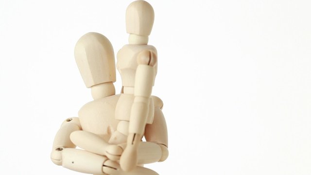 wooden figures of child sitting on hands of his parent