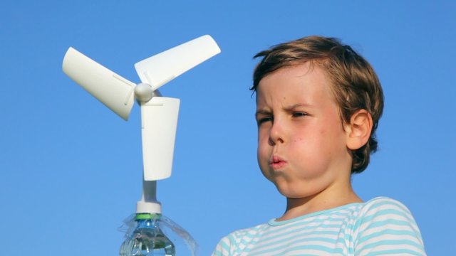 boy plays with a wind-driven generator against sky